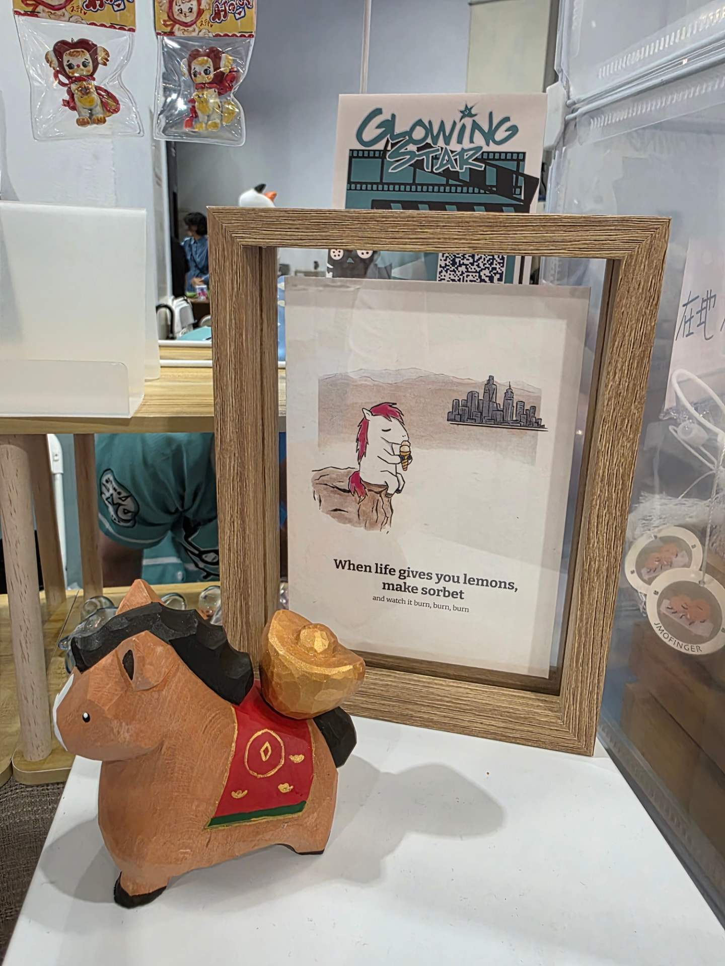 A framed print and a carved wooden horse figurine on the Glowing Star display table at T-TASTE Taipei 2026